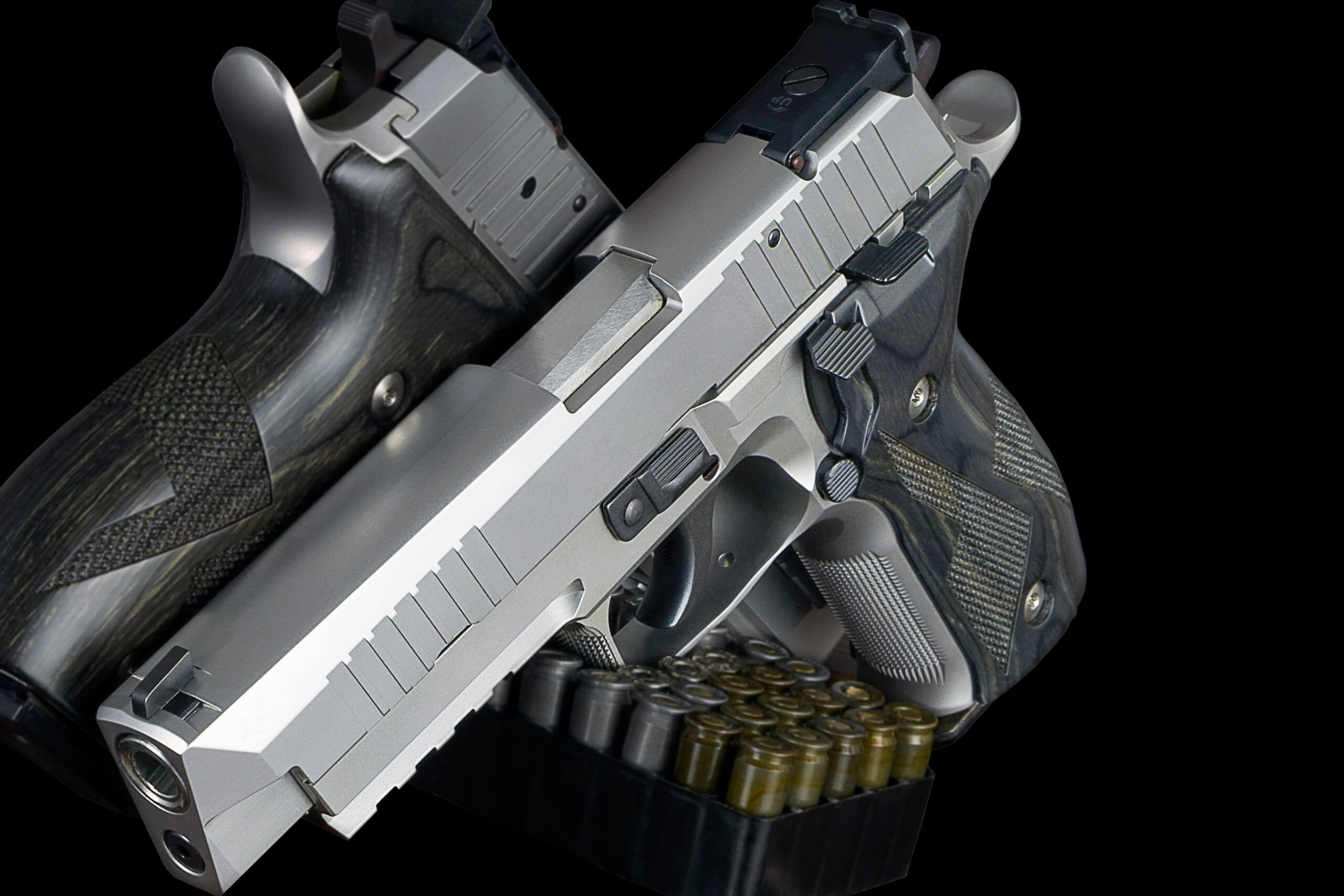 Two Stainless Handguns Sitting On Top Of Ammo