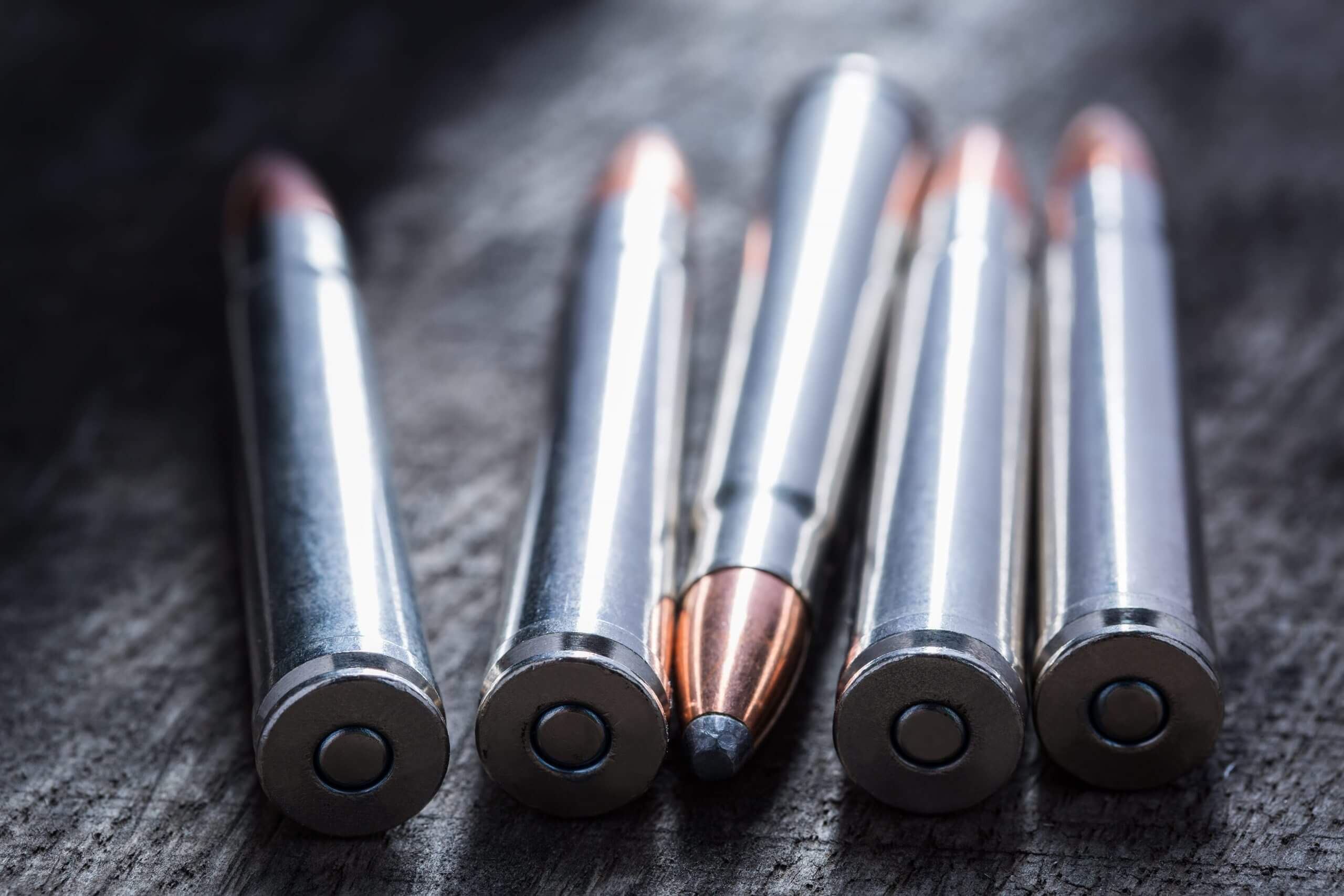 5 Rounds Of Ammo Sitting On Wood Tabletop