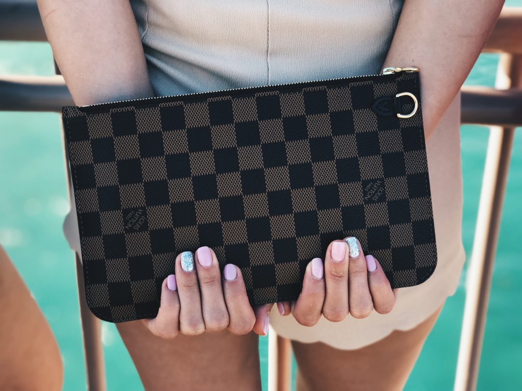 woman holding Louis Vuitton clutch